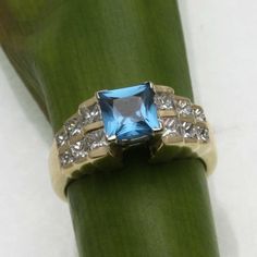 "This is a beautiful vintage ring! This stunning ring is made of 14k yellow gold. It is an elegant \"step\" style mounting with a 2 carat (approximate) square London blue topaz in the center. The topaz measures 6mm by 6mm and is set in a 4 prong head. On both sides of the topaz are 6 princess cut diamonds that step down in 3 steps, and graduate down in size from top to bottom. The princess cut diamonds are channel set. They are very white and sparkly, the diamonds are H-I in color and VS2-SI1 in Classic Princess Cut Blue Topaz Ring, Classic Blue Topaz Princess Cut Ring, Classic Blue Topaz Ring With Princess Cut, Classic Princess Cut Topaz Ring With Center Stone, 6 Princess, Topaz Diamond Ring, Ring Princess Cut, Beautiful Rings Vintage, Diamond Ring Princess Cut