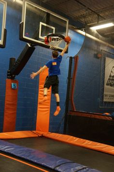 a young boy jumping on an inflatable trampoline while playing with a basketball