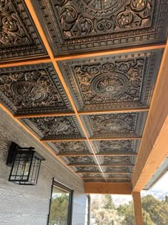 an intricately designed metal ceiling in a house with wood trimming and glass doors