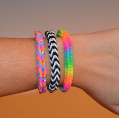 three different colored bracelets on a person's arm, one with an arrow and the other with a chevron pattern