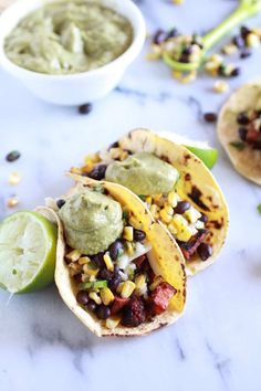 three tacos with black beans, corn and guacamole on the side