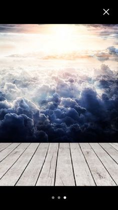 an empty wooden floor in front of a cloudy sky