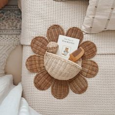 a wicker basket with a book in it on top of a white bed frame