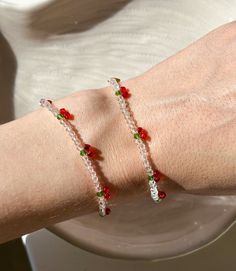 a woman's arm wearing two bracelets with red and green beads on it