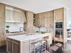 a kitchen with wooden cabinets and white counter tops, two stools are in front of the center island