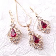 "Elegant Victorian inspired drop earrings, pendant, or necklace set with ruby red crystal center jewels bordered by swirls of pave set clear diamante. The metal is nickel-free with your choice of rose gold, silver, or gold plating. The earrings are 2\" (5 cm) long and .8\" (2cm) wide. The pendant is 1.5\" long on a chain that is adjustable from 16\"-18\" long. Ships quickly in a free gift box! I stock crystals in the full rainbow of colors and can customize this design in many colors to match yo Elegant Cubic Zirconia Jewelry Sets For Valentine's Day, Red Crystal Dangle Jewelry, Formal Red Dangle Jewelry Sets, Red Crystal Jewelry Sets For Valentine's Day, Red Crystal Jewelry With Matching Earrings, Elegant Red Jewelry Sets With Sparkling Stones, Rose Gold Ruby Jewelry For Parties, Valentine's Day Ruby Jewelry With Matching Earrings, Red Jewelry Sets For Gifts