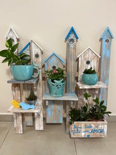 three wooden birdhouses with plants and potted plants on them, one is painted blue