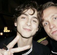 two young men posing for the camera with their fingers in the shape of a peace sign