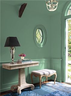 a room with green walls and blue rugs on the floor next to a table