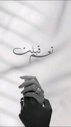 two hands holding each other in front of a white and black background with arabic writing