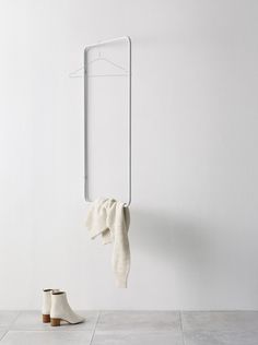 a pair of white boots and a towel hanging on a hook in a room with tile flooring