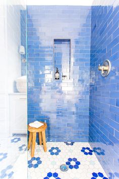 a blue tiled bathroom with stool and shower