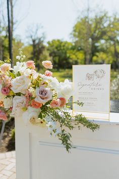 a bouquet of flowers sitting on top of a white table next to a card holder