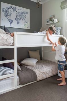 two children are playing on the bunk beds in this room, and one is trying to climb up