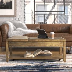 a living room with a couch, coffee table and laptop on top of a book