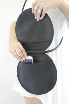 a woman holding a black purse with her cell phone in it