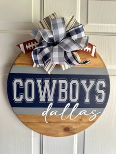 a wooden sign hanging on the side of a door that says cowboys dallas with footballs