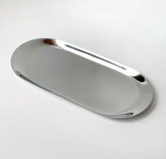 a silver oval shaped tray on a white surface with no one around it or someone else