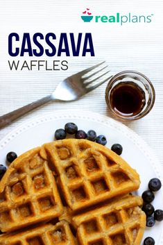 a white plate topped with waffles covered in blueberries next to a fork