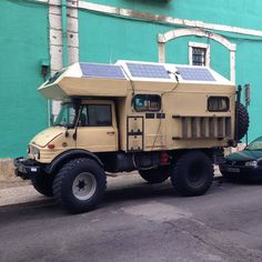 a large truck with a solar panel on the roof parked in front of a building