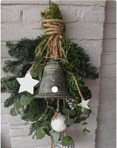 a bell hanging from the side of a brick wall with greenery and white ornaments