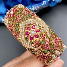 Featuring a broad gold plated silver jadau kada/bangle made on sterling silver with gold plating. It has been intricately studded with ruby like red stones, emerald like green stones and freshwater pearls. The bangle comes openable in size 2inch 5 anna and this design can be customized to your size. Jadau Kada, Kada For Women, 22k Gold Jewelry Necklaces, 22k Gold Jewelry, Like Green, Red Stones, Pearl Necklace Set, Bangles Making, Green Stones