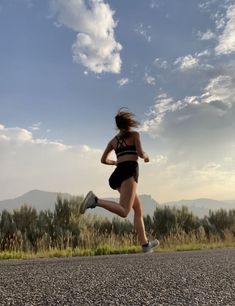 a woman is running down the road with her leg in the air and headphones on