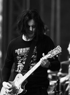 a man with long hair playing an electric guitar