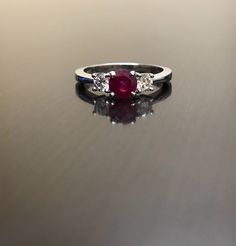 DeKara Designs Collection Classic/Modern Three Stone Diamond Past Present and Future Engagement Ring. Metal- 90% Platinum, 10% Iridium Stones- 1 Round Natural Pigeon Blood Ruby 0.71 Carats, 2 Round Diamonds, G color VS1 clarity, .44 carats. Art Deco Inspired Beautiful Pigeon Blood Red Ruby Three Stone Diamond Engagement Ring Made in Platinum. There is a vibrant and fiery round ruby that is professionally set in between four prongs. There is one round fiery diamond on each side of the the ruby th Luxury Gia Certified White Gold Ruby Ring, Gia Certified Classic Ruby Ring With Diamond Accents, Gia Certified Fine Jewelry Ruby Ring In Platinum, Gia Certified Platinum Ruby Ring In Fine Jewelry, Gia Certified Platinum Ruby Ring, Elegant Gia Certified Ruby Ring With Round Cut, Gia Certified Round Cut Ruby Ring Fine Jewelry, Gia Certified Round Cut Ruby Ring, Luxury Red Three Stone Jewelry