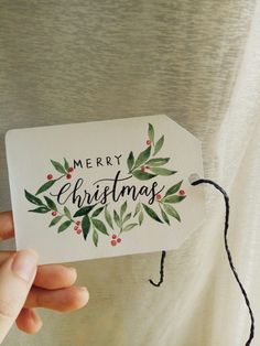 someone holding up a merry christmas card with holly and berries on the front, which reads merry christmas