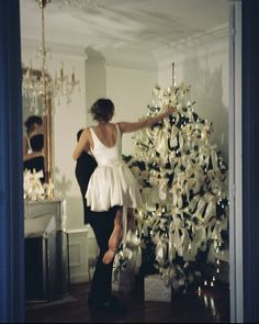 a woman standing next to a christmas tree