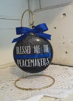 a glass ornament with a blue ribbon on it that says, blessed are the peacemakers