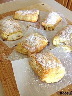 several pastries sitting on top of wax paper covered in powdered sugar and sprinkles