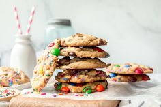 a stack of cookies with sprinkles and candies on a cutting board