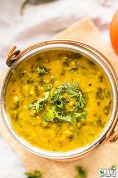 a metal bowl filled with soup and garnished with cilantro