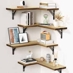 three wooden shelves with books, pictures and other items on them against a white wall