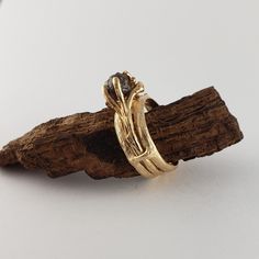 a gold ring sitting on top of a piece of driftwood with a black diamond in the center