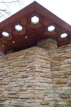 a stone wall with lights on top of it in front of a wooden roof overhang