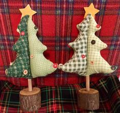 three small christmas trees on wooden sticks in front of a red tarp couch with plaid fabric