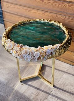 a green and gold tray with shells on it sitting on a wooden floor next to a wall