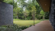 a wooden porch with swings and trees in the back ground, next to a grassy area