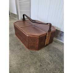 a large brown leather trunk sitting on the ground in front of a white wall and door