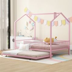 a child's bed with a pink frame and mattress in a room decorated with bunting flags