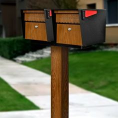 two mailboxes are attached to a wooden post in front of a sidewalk and grass area