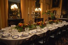 a long table is set with place settings and flowers on it for an elegant dinner