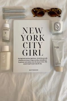 the contents of a new york city girl travel bag laid out on a white sheet