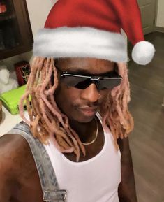 a man with dreadlocks wearing a santa hat and sunglasses in a kitchen area