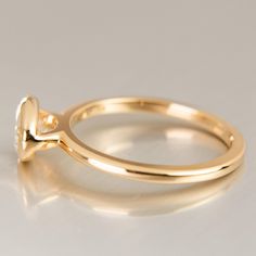 a gold ring with a single diamond in the middle on a white surface, close up