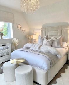 a bedroom with white furniture and chandelier hanging from the ceiling