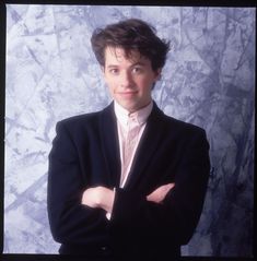 a man wearing a suit and tie posing for a photo with his arms crossed in front of him